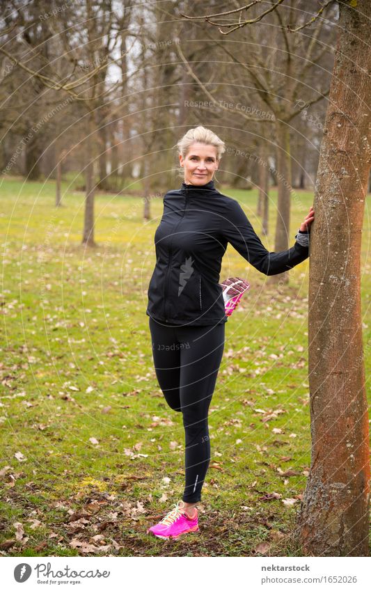 Frau, die sich im Park ausdehnt. Lifestyle Körper Wellness Sport Mensch Erwachsene Fitness Lächeln stehen sportlich dünn Freundlichkeit Lockerungsübungen