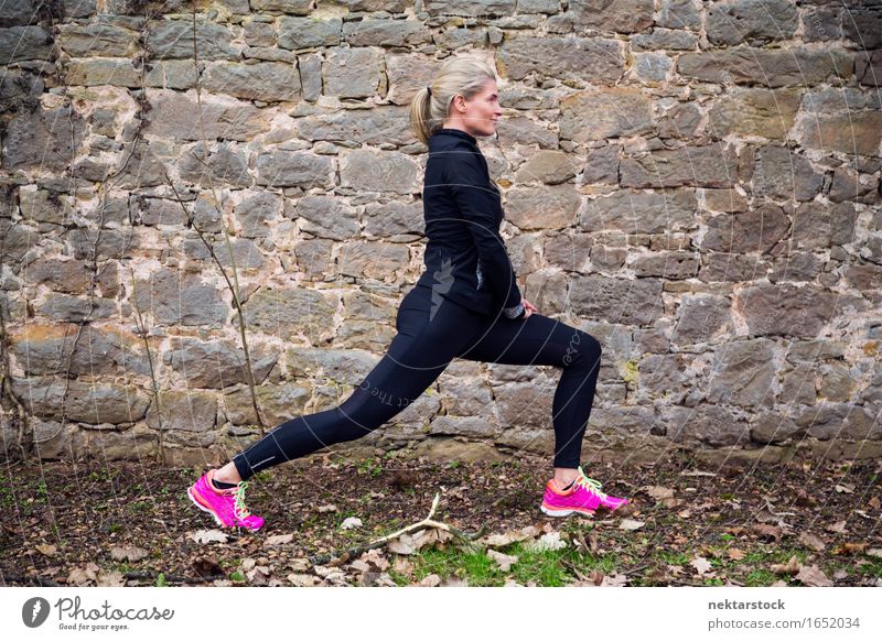 Frau, die ihren Körper vor der alten Mauer im Park ausstreckt. Lifestyle Wellness Sport Mensch Erwachsene Stein berühren Fitness sportlich Mobilität üben