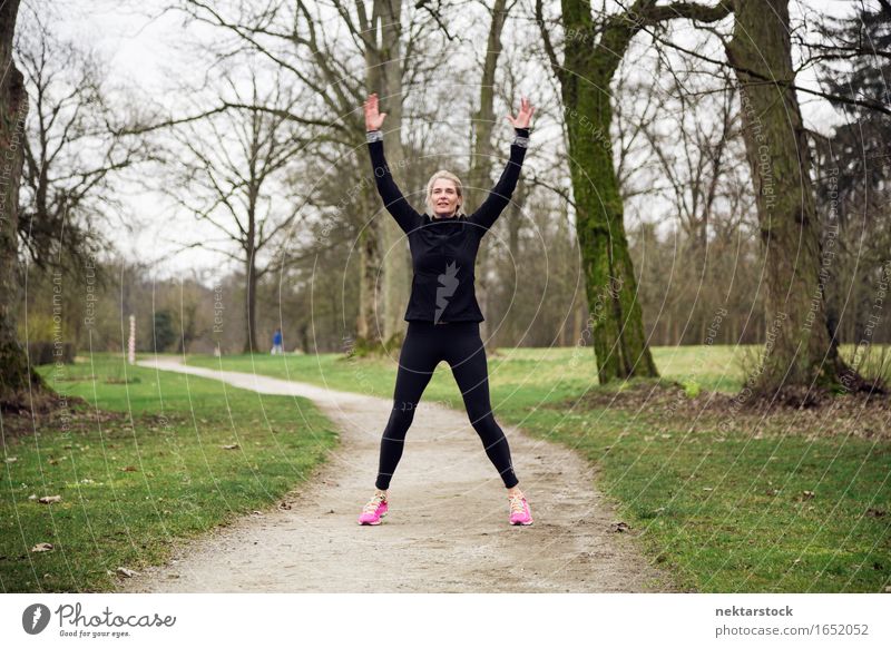 Frau beim Training am Wintertag Lifestyle Freude Glück Körper Wellness Sport Mensch Erwachsene Arme Baum Park Fitness Lächeln springen sportlich üben Gesundheit