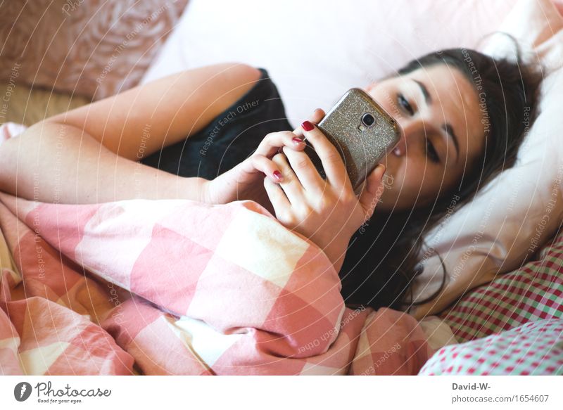 junge Frau liegt im Bett und schaut auf Ihr Smartphone Handy Jugendliche Liebeskummer schreiben tippen konzentriert vertieft