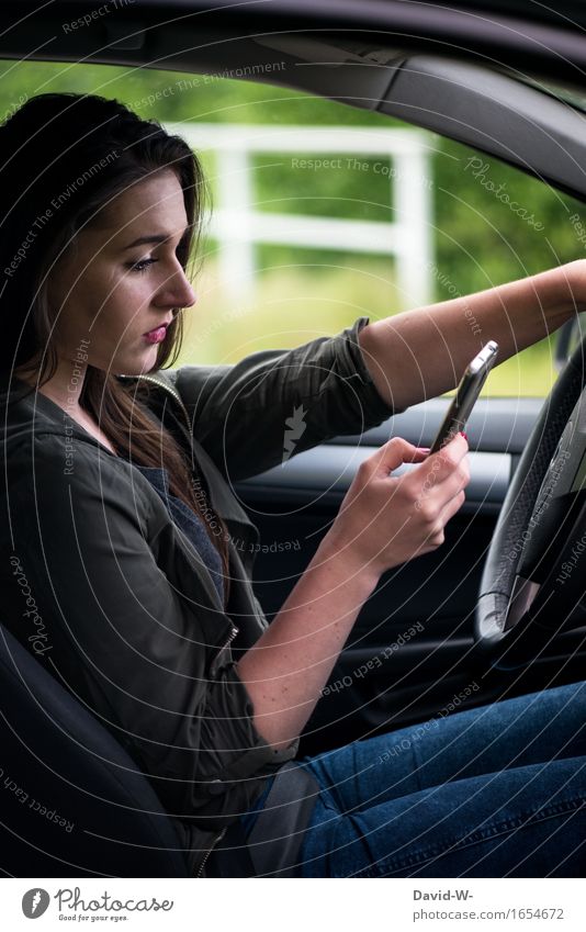 junge Frau benutzt am Steuer ihrers PKWs ein Handy Auto gefahr verbot leichtsinnig gefährdung Straßenverkehr autofahren Abgelenkt
