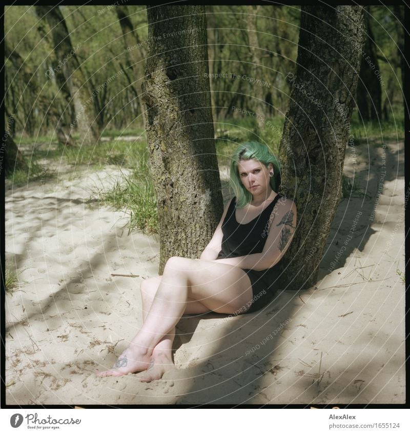 junge Frau mit türkisen Haaren sitzt barfuß an einen Baum gelehnt im Strand- Wald und schaut in die Kamera Erholung Ferien & Urlaub & Reisen Ausflug