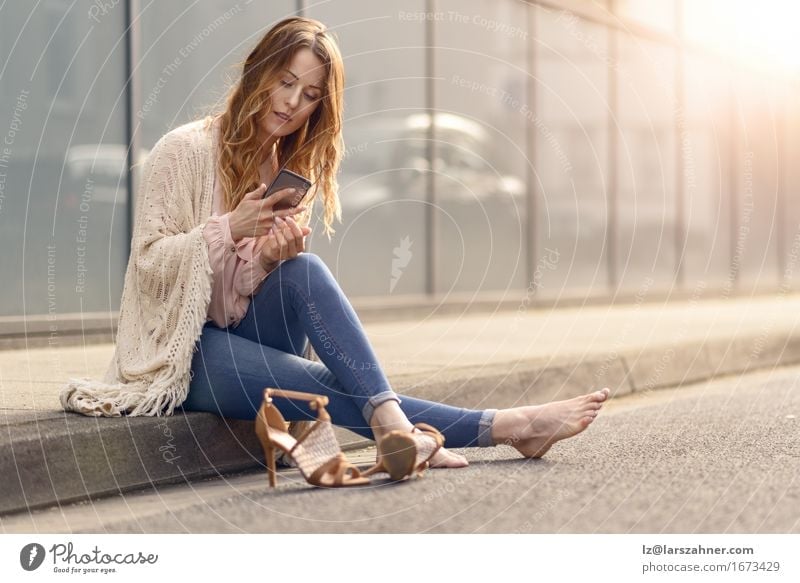 Attraktive Lesung der jungen Frau an ihrem Handy Lifestyle schön Gesicht Erholung lesen sprechen Telefon PDA Erwachsene Straße Damenschuhe Behaarung sitzen