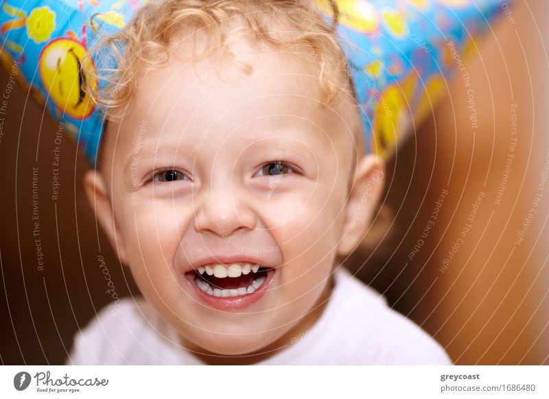 Nahaufnahme Gesichtsporträt eines fröhlich lachenden kleinen Jungen mit gewelltem blondem Haar, der direkt in die Kamera schaut Freude Glück Sommer