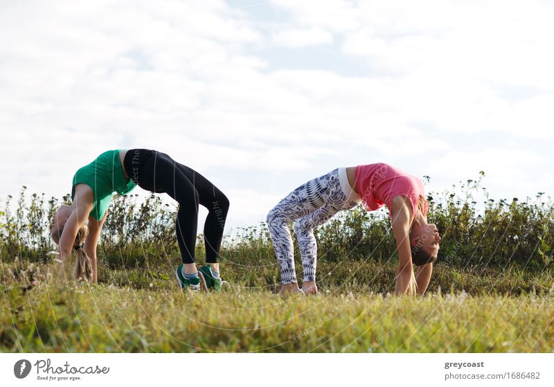 Zwei junge Mädchen trainieren gemeinsam im Freien: Dehnungsübungen Sommer Garten Mensch Junge Frau Jugendliche Erwachsene 2 18-30 Jahre Natur Landschaft Gras