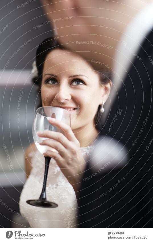 Elegante junge Frau in einem weißen Kleid trinkt Weißwein bei einer Veranstaltung und lächelt zu ihrem männlichen Partner auf Alkohol Champagne Glück schön