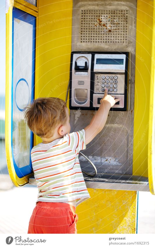 Junger Junge spricht in einer gelben Telefonzelle mit dem Telefon Kind sprechen Funktelefon Baby Kindheit 1 Mensch 3-8 Jahre Straße blond bezahlen hören