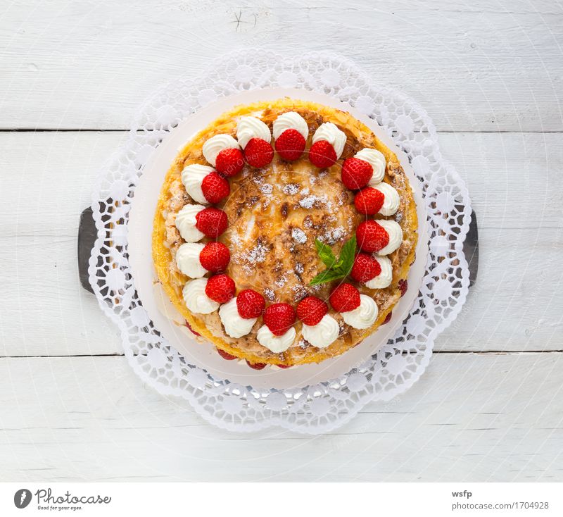 Baisertorte mit Erdbeer Joghurt auf weißem Holz Kuchen Dessert Erdbeeren Torte Schaumgebäck Sahne Tortenspitze Backwaren backen Biskuit Minze süßes