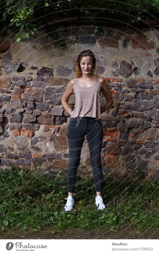 angelockt Freude schön sportlich Junge Frau Jugendliche 18-30 Jahre Erwachsene Landschaft Efeu Mauer Wand Jeanshose Top Turnschuh blond langhaarig Kommunizieren