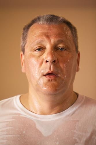 Müde aussehende heiß schwitzende Mann mittleren Alters nach einem Training, Nahaufnahme Kopf und Schultern Porträt Blick direkt in die Kamera Gesicht