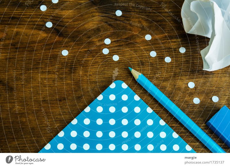 Punkte sammeln: blaues Papier mit weißen Punkten, Bleistift, Radiergummi und ein zerknüllter Zettel auf einem Holz - Schreibtisch Schule lernen