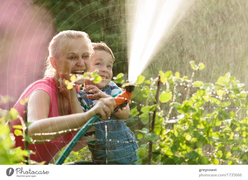 Junge Mutter und niedlichen Sohn spielen mit Wasserschlauch im Garten Freude Glück Spielen Sommer Kind Erwachsene Familie & Verwandtschaft 2 Mensch Natur