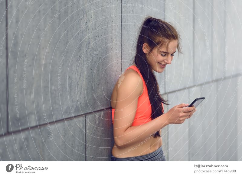 Sportliche junge Frau, die Nachrichten am Telefon überprüft Gesicht Sommer PDA Erwachsene 1 Mensch 18-30 Jahre Jugendliche Wärme brünett Fitness Lächeln stehen