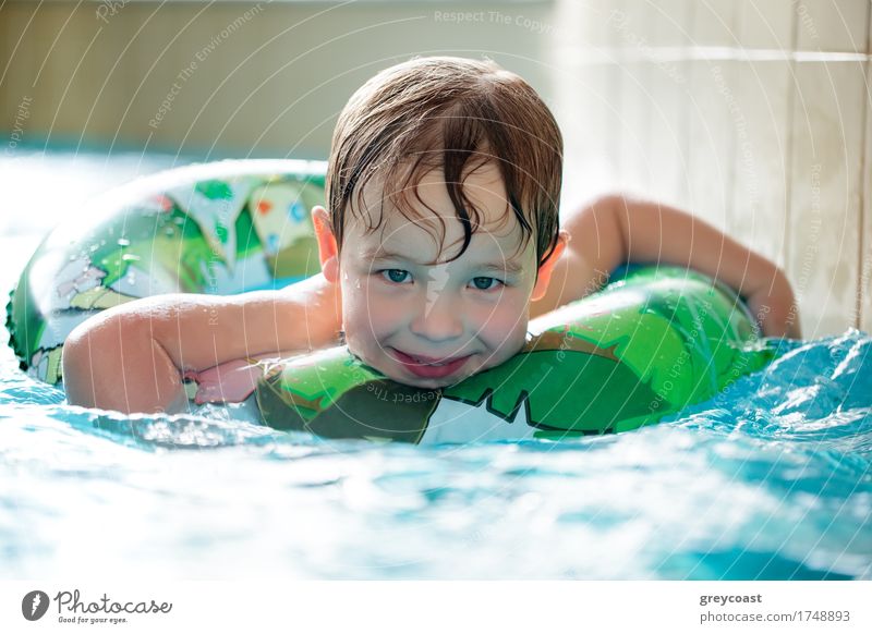 Junger Junge in aufblasbarem Schlauch schwimmen mit einem großen Lächeln auf seinem Gesicht Freude Glück Erholung Spa Schwimmbad Kind 3-8 Jahre Kindheit Wasser