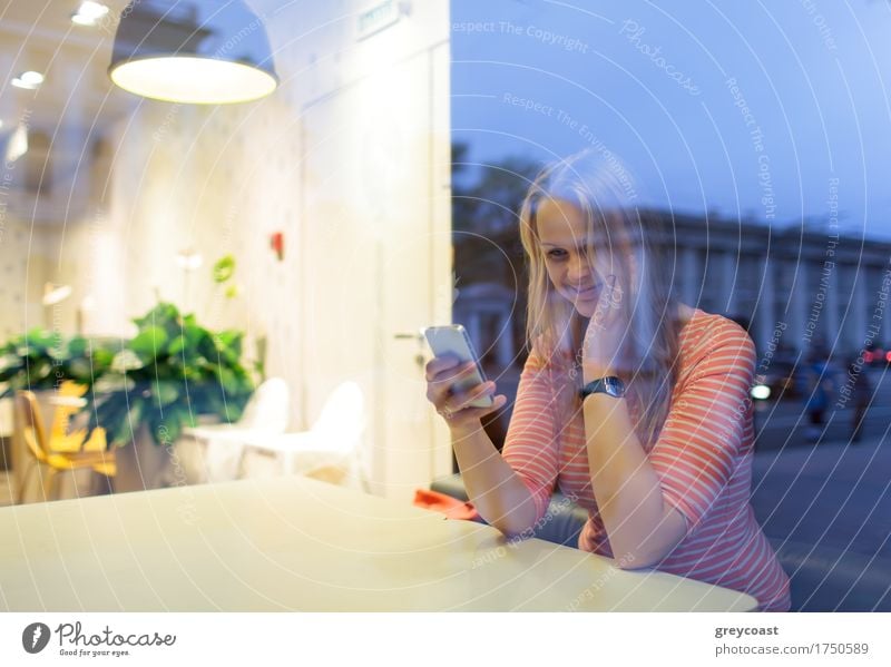 Glückliche Frau in der Cafeteria Lesen oder Tippen sms. Blick durch das Glas mit Stadt Reflexion Restaurant Telefon PDA Junge Frau Jugendliche 1 Mensch