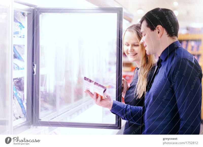 Paar in der Tiefkühlabteilung eines Lebensmittelladens, das Lebensmittel aus dem Gefrierschrank nimmt kaufen Glück Mensch Frau Erwachsene Mann