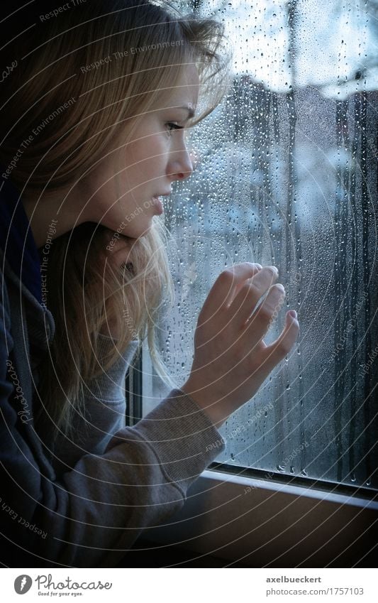 Frau, die durch Fenster mit Regentropfen schaut Mensch feminin Junge Frau Jugendliche Erwachsene 1 18-30 Jahre Herbst Winter Wetter schlechtes Wetter blond