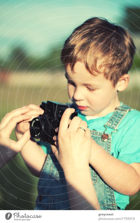 Mutter hilft ihrem kleinen Sohn, seine ersten Bilder im Freien zu machen. Fokus auf Mütter Hände. Instagram Stil Farbe getönt Sommer Kind Fotokamera Junge