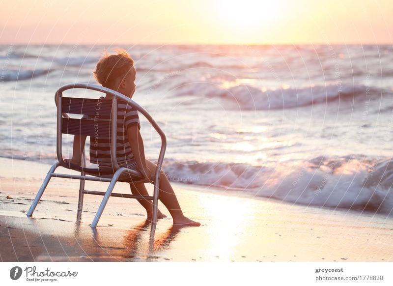 Kleiner Junge sitzt allein auf dem Stuhl am Strand und schaut auf Meer Wellen. Abendsonne überstrahlt Wasser Erholung Ferien & Urlaub & Reisen Sommer Kind 1