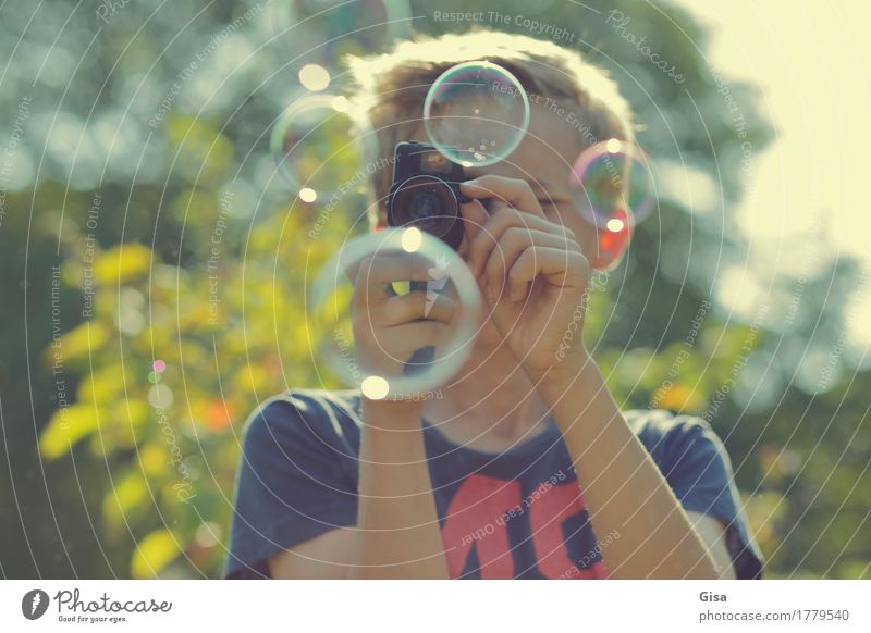 Bub filmt  im Freien mit einer Super-8-Kamera Seifenblasen bei Sonnenlicht. Freizeit & Hobby filmen Sommer Garten Videokamera Mensch maskulin Junge 1 8-13 Jahre