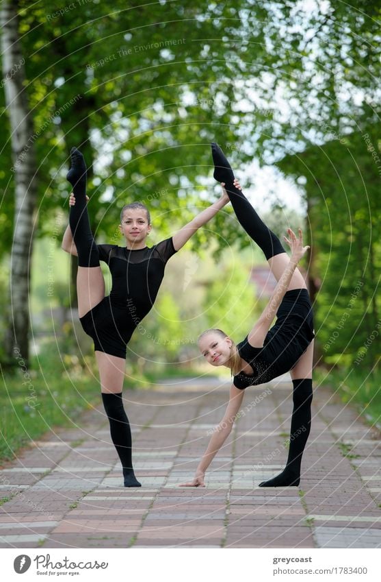 Zwei jugendliche Rhythmische Sportgymnastinnen zeigen ihre Dehnbarkeit und Flexibilität. Körper Sommer Mädchen Jugendliche 2 Mensch Menschengruppe Kunst Straße