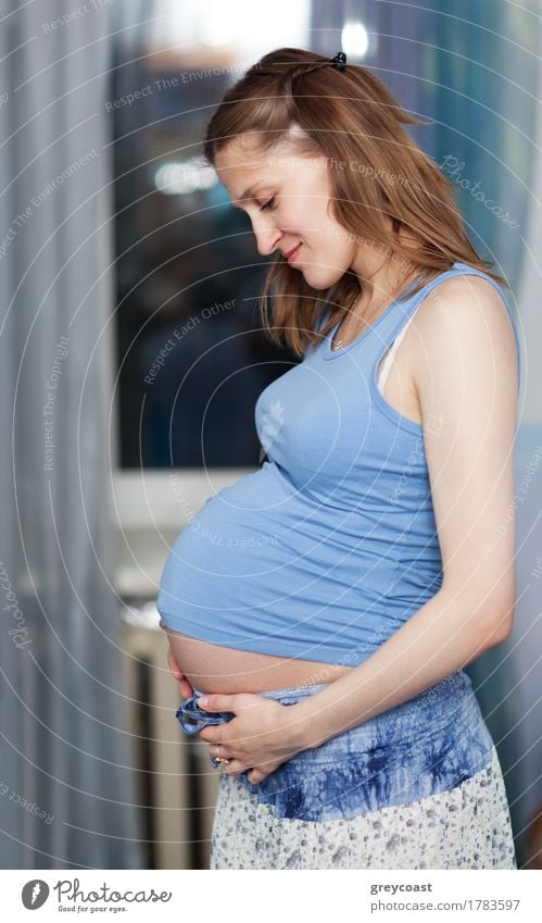 Schwangere Frau steht im Raum mit ihren Händen auf dem Bauch Körper Leben Junger Mann Jugendliche Mutter Erwachsene Hand 1 Mensch 18-30 Jahre brünett berühren