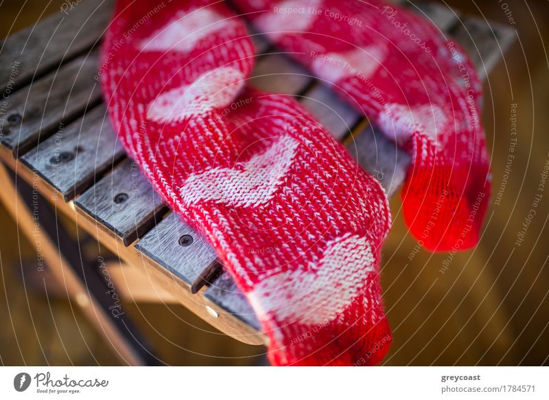 Nahaufnahme von roten gestrickten Socken mit niedlichen Herz-Muster auf Holzstuhl Möbel Stuhl Frau Erwachsene Wärme Bekleidung Schuhe Liebe hell Mut Romantik