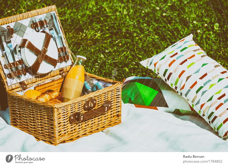 Picknick-Korb-Lebensmittel auf weißer Decke mit Kissen im Sommer Frucht Apfel Orange Croissant Ernährung Essen Frühstück Mittagessen Saft Geschirr Flasche
