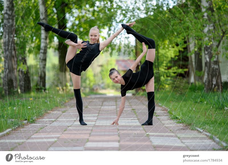 Zwei junge Turner Mädchen zeigen ihre Flexibilität und Stretching posieren im Freien an einem Sommertag Glück Körper Sport Kind Mensch 2 13-18 Jahre Jugendliche