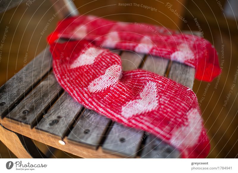 Nahaufnahme eines Paares roter Wollsocken mit Herzmuster auf einem Holzstuhl liegend Möbel Stuhl Frau Erwachsene Wärme Balkon Garten Bekleidung Schuhe Liebe