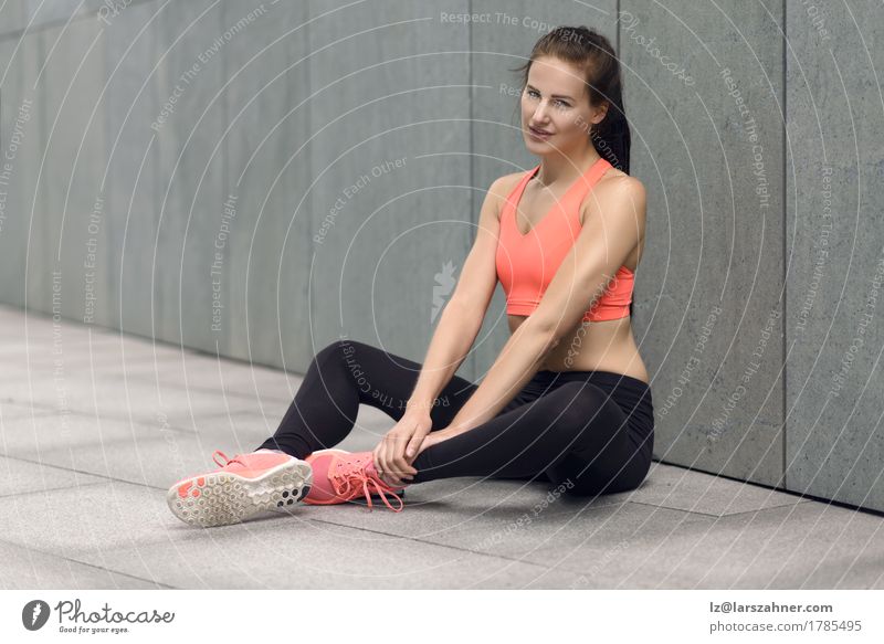 Athletische junge Frau, die auf der Betonpflasterung sitzt Lifestyle Zufriedenheit feminin Erwachsene 1 Mensch 18-30 Jahre Jugendliche Strumpfhose brünett
