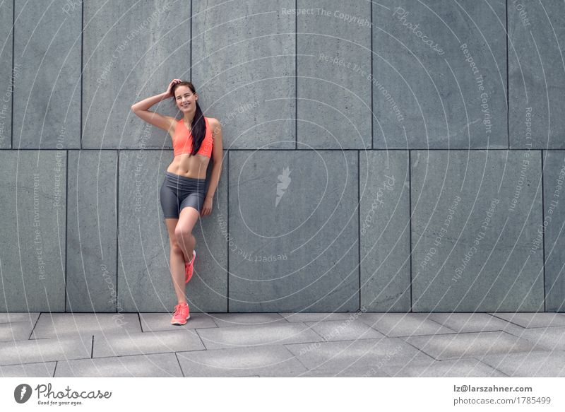 Attraktive sportliche junge Frau, die auf einer Wand sich lehnt Lifestyle Glück Haut Sommer Erwachsene 1 Mensch 18-30 Jahre Jugendliche brünett Lächeln stehen