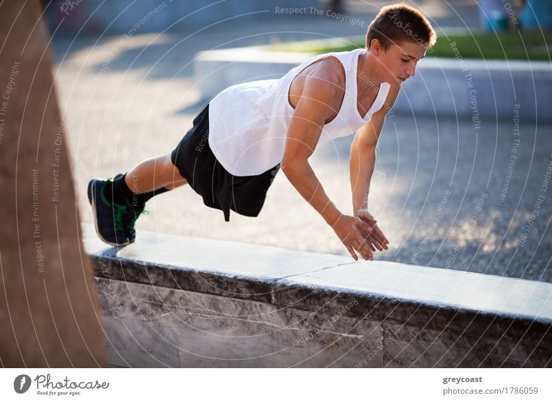Junger sportlicher Mann macht Liegestütze auf einem Grenzstein in der Stadt. Städtische Übung und Training Lifestyle Körper Sport Junger Mann Jugendliche