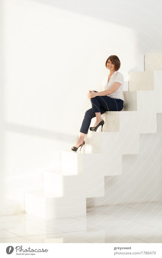 Lächelnde Geschäftsfrau sitzt auf den Stufen einer modernen Leiter elegant Stil Design schön Windstille Büro Business Laufmasche Mensch Frau Erwachsene 1