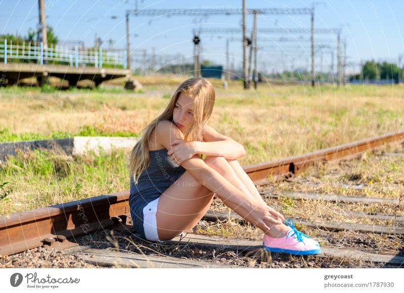 Einsames und trauriges Teenager-Mädchen, das auf einer rostigen Eisenbahnschiene auf dem Land sitzt. Adoleszenz Probleme Sommer Frau Erwachsene Jugendliche