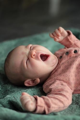 Guten Morgen feminin Baby 1 Mensch 0-12 Monate liegen Müdigkeit Bewegung Kindheit gähnen strecken rosa grün Decke Farbfoto Innenaufnahme Tag Zentralperspektive