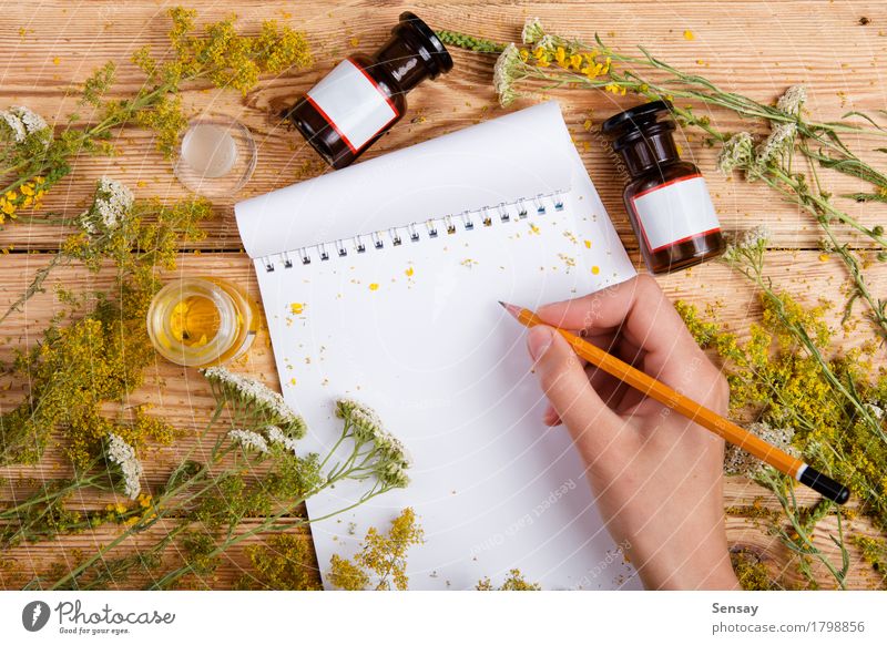 Hand schreiben ein Rezept im Editor auf Holztisch, Kräuter um Kräuter & Gewürze Flasche schön Gesundheitswesen Alternativmedizin Medikament Massage Tisch Küche