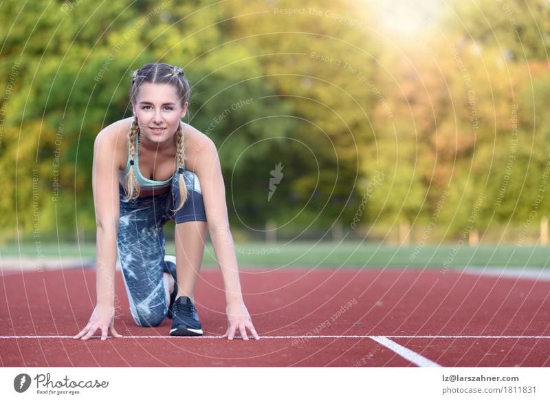 Athletische junge Frau in einer Starterposition Glück Gesicht Sport Rennbahn Erwachsene 1 Mensch 18-30 Jahre Jugendliche blond Fitness Lächeln Sonnenuntergang