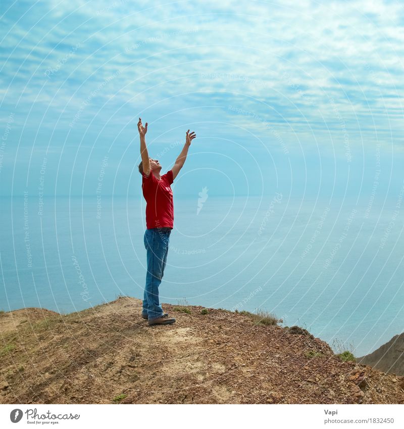 Glücklicher Mann, der mit erhobenen Händen auf einer Klippe steht und auf das Meer schaut Lifestyle Freude Wellness stimmig Wohlgefühl Erholung Meditation