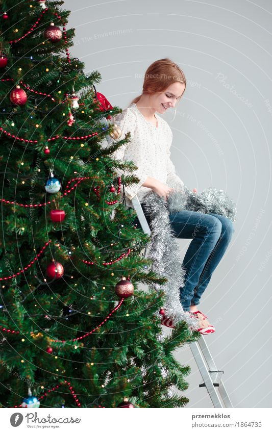 Junges Mädchen, welches die Weihnachtsdekoration auspackt, die auf einer Leiter sitzt Lifestyle Freude Dekoration & Verzierung Feste & Feiern