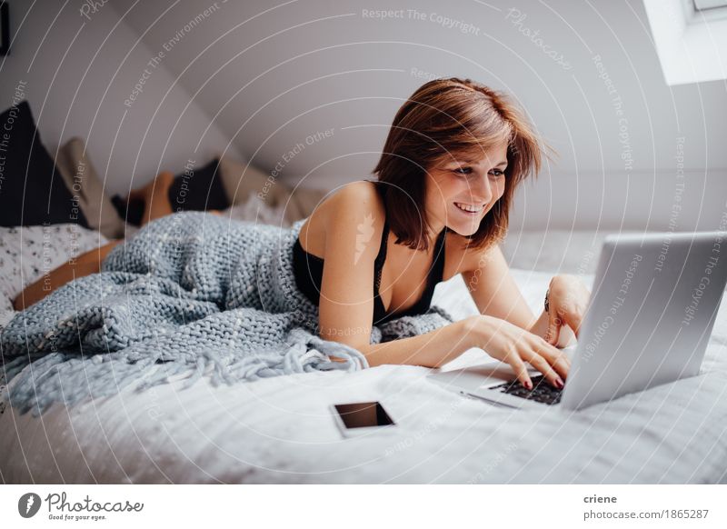 Junge kaukasische Frauen, die in Bett mit Laptop legen Lifestyle Freude Häusliches Leben Wohnung Schlafzimmer Bildung lernen Student Arbeit & Erwerbstätigkeit
