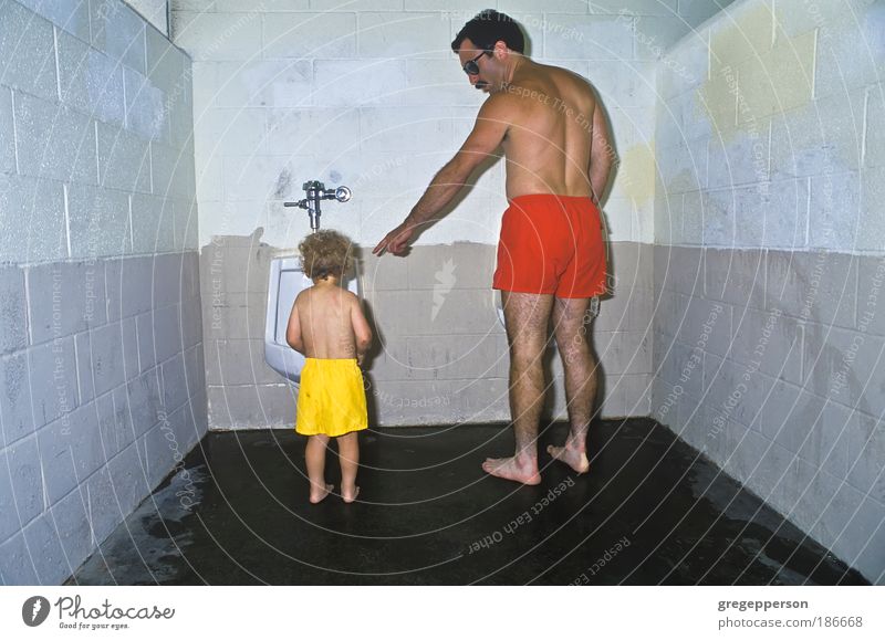 Vater und Sohn in der öffentlichen Toilette. Junge Erwachsene 1-3 Jahre Kleinkind Badehose Pissoir Hilfsbereitschaft Verantwortung gewissenhaft Neugier Sorge