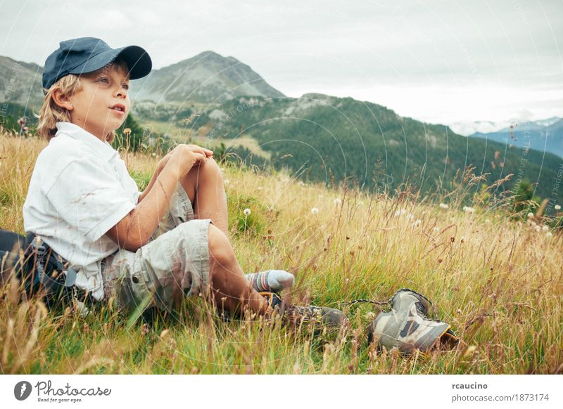 Junge macht eine Pause in einer Wiese während einer Bergwanderung Erholung Ferien & Urlaub & Reisen Tourismus Abenteuer Sommer Berge u. Gebirge wandern Kind