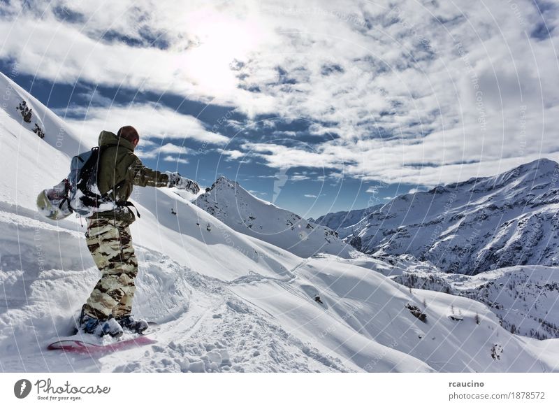 Snowboarder geht bergab über eine verschneite Berglandschaft. Ferien & Urlaub & Reisen Winter Schnee Berge u. Gebirge Sport Skifahren Junge Mann Erwachsene