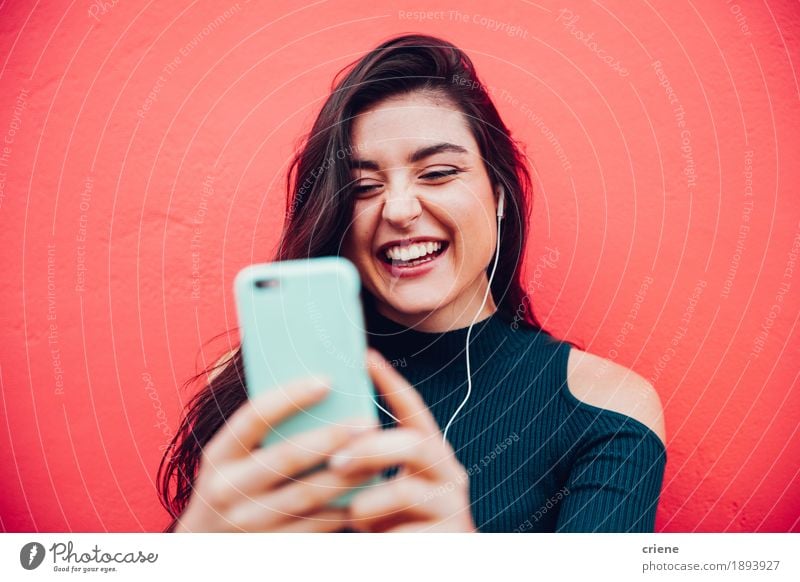 Junges glückliches Frauenvideo, das mit intelligentem Telefon plaudert Lifestyle Freude Musik Handy Headset MP3-Player PDA Technik & Technologie