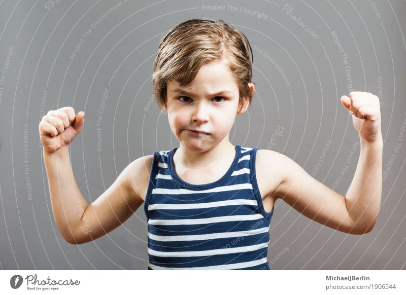 Sechsjähriger Junge zeigt seine Bizeps-Muskeln Gesicht Sport Erfolg Kind Mensch Kleinkind 3-8 Jahre Kindheit Wachstum sportlich Coolness stark grau Ausdauer