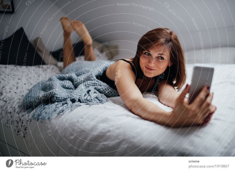 Junger weiblicher Erwachsener, der zu Hause auf das Bett nimmt selfie legt Lifestyle Freude Glück Erholung Schlafzimmer Flirten Handy PDA Technik & Technologie
