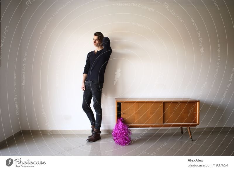junger Mann eine einem hellen Raum mit Sideboard und lila Perücke darin Stil Freude Feste & Feiern Junger Mann Jugendliche 18-30 Jahre Erwachsene Schrank rosa