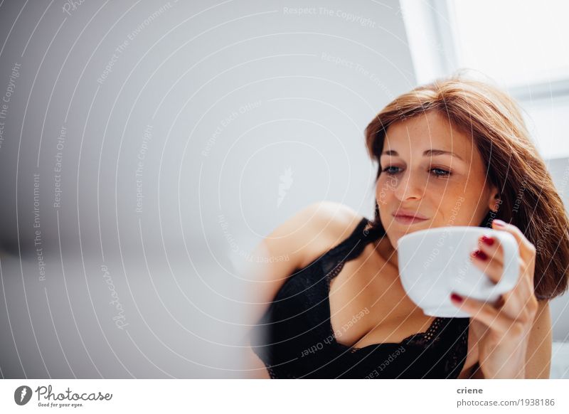 Junge kaukasische Frau, die in Betttrinkbecher Kaffee legt Lifestyle Freude Wohnung Schlafzimmer Notebook Technik & Technologie Internet Mensch feminin