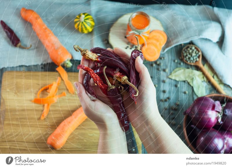 Zwei weibliche Hände, die einen getrockneten glühenden Pfeffer halten Gemüse Frucht Kräuter & Gewürze Ernährung Vegetarische Ernährung Saft Löffel Körper Tisch